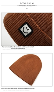 Close-up of caramel brown ribbed knit beanie featuring a square smiley face patch detail