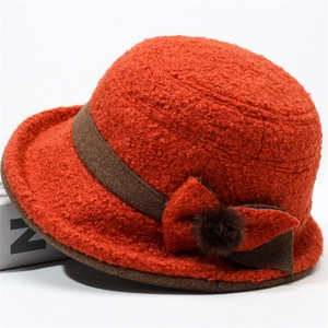 Chic orange winter bucket hat with bow detail and faux fur pom for cold weather