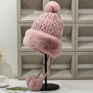 Pink chunky knit beanie with faux fur trim and pom-pom ties for winter warmth