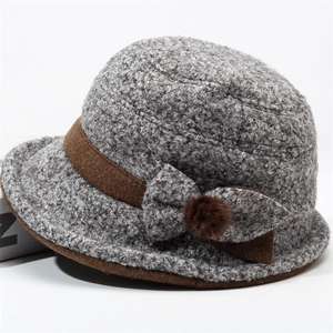 Close-up of grey textured knit cloche hat with a bow and brown pom-pom detail