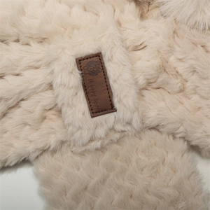 Close-up of beige fleece hat texture with a cute baby bear leather patch detail
