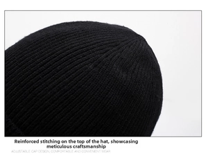 Detailed close-up of reinforced stitching on top of the black ribbed knit beanie hat