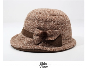 Detail of brown fleece knit bucket hat featuring a decorative bow and plush ball