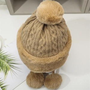 Detail of chunky knit trapper hat with soft faux fur trim and three fluffy pom poms
