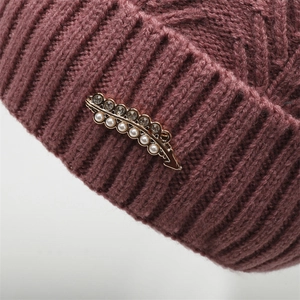 Detailed knit texture and elegant leaf brooch with pearls on winter knitted hat
