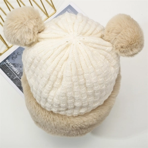 Dettaglio del cappello invernale a maglia con bordo in ecopelliccia e graziosi pompon