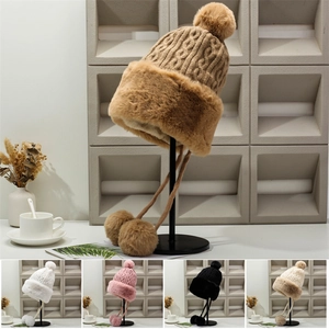Detailed close-up of thick knit cable pattern and fluffy faux fur trim on a winter hat