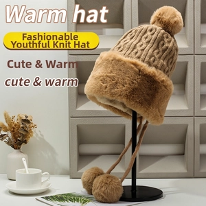 Detail of dark khaki knitted hat with thick faux fur trim and decorative pom poms