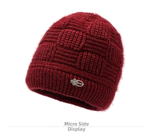 Detail of dark red knit beanie featuring checkerboard texture and floral metal ornament
