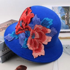 Detailed close-up of vibrant floral embroidery on a royal blue wool cloche hat