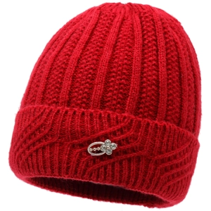 Detail of red knit beanie with thick texture and silver floral emblem decoration