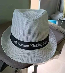 Close-up of white breathable woven straw fedora hat with black printed ribbon detail