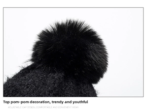 Detail of a large fluffy faux fur pom-pom on top of a black chenille knit beanie