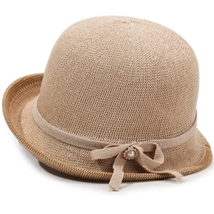 Detailed view of beige knitted sun hat with elegant pearl bow and fine texture