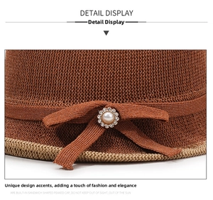 Close-up of brown straw sun hat featuring a bow with pearl and rhinestone detail