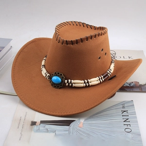 Chapeau de cowboy marron avec perles turquoise posé sur des magazines de mode