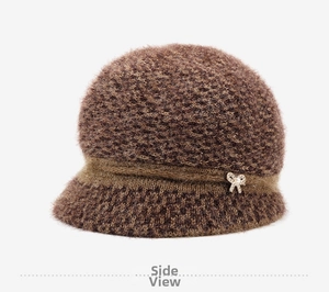Detail of plush knitted cloche hat featuring a golden bow with pearl and soft fuzzy texture