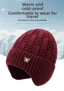 Detail of burgundy knit winter hat with decorative pearl butterfly pin and ear protection