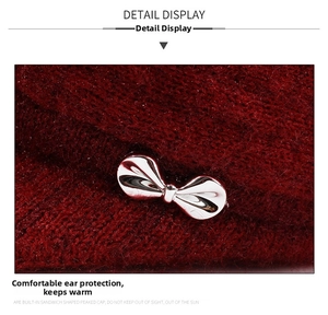 Close-up of deep red knitted hat featuring a polished silver metal bow and warm texture