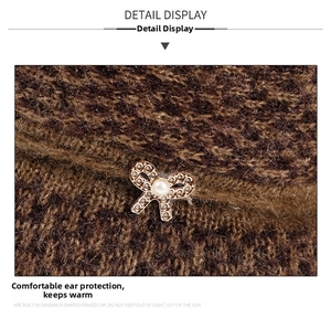 Detailed close-up of thick knit winter hat featuring a gold bow and faux pearl accent