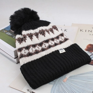 Close-up of diamond lattice knit hat with large faux fur pompom on minimalist background