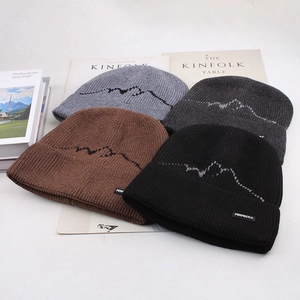 Detailed close-up of mountain jacquard beanies in grey, brown, and black colors