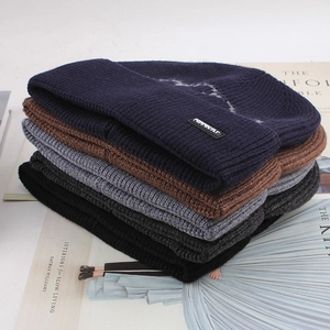 Close-up showing colorful winter knitted beanies in black, navy, brown, and grey textures