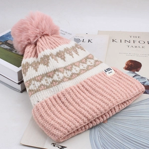 Close-up of pink and cream diamond knit pattern with large fluffy pom-pom detail