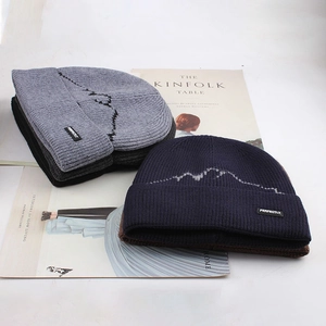 Detail of knitted winter beanies with mountain pattern and side logo on a clean background