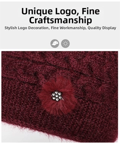 Dettaglio del cappello in maglia bordeaux con motivo a trecce e fiore di strass