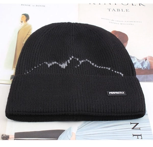 Detail of black knit beanie featuring grey mountain patterns and Perfectly label