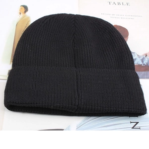Close-up of fine ribbed knitting and folded cuff on black winter beanie cap