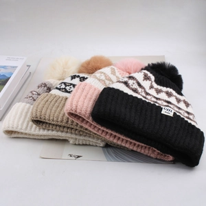 Detail view of colorful knit beanies with large fur pom-poms and diamond texture
