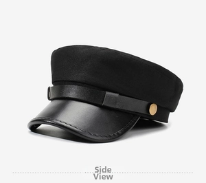 Détail d'une casquette gavroche noire avec visière en cuir brillant et bouton doré