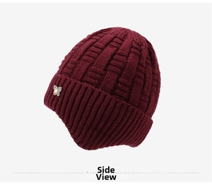 Side view of dark red knitted winter hat with textured grid pattern and pearl bow