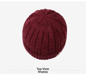 Top down detail of burgundy knit beanie featuring thick texture and metal cross pendant