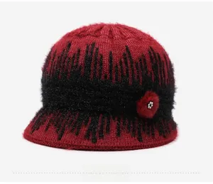Detail of winter knit bucket hat with red wool flower and pearl accent on textured fabric