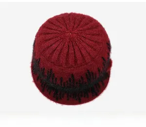 Flat lay of wine red knit hat with fuzzy texture, black zigzag pattern, and glitter details