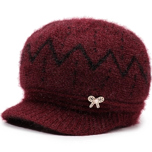 Detail of burgundy knitted hat with fleece lining, sequins, and pearl bow ornament