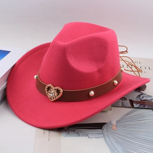 Detail of fuchsia wool cowboy hat featuring pearl-studded leather band and golden heart buckle