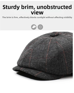 Detail of grey herringbone newsboy cap fabric with red plaid lines and stiff brim
