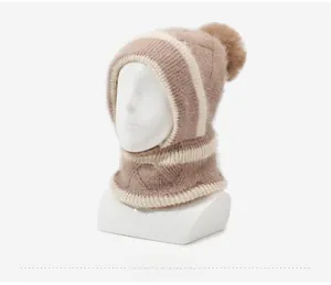 Détail du bonnet en maille épaisse couleur chameau avec cache-cou intégré et pompon en fourrure