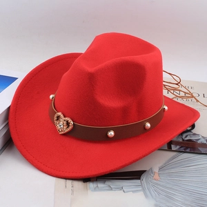 Detail of red wool cowboy hat with brown leather band, white pearls and gold heart charm