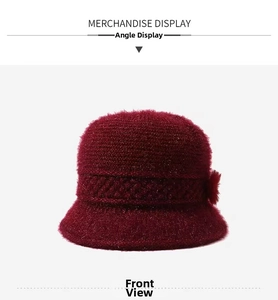 Close-up of dark red knitted basin hat with plush flower and shimmering texture