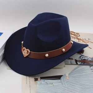 Detail of navy felt fedora with heart-shaped badge and pearl leather band on a magazine