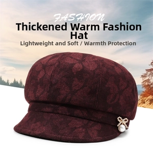 Detail of burgundy newsboy hat with embossed floral texture and pearl bow ornament