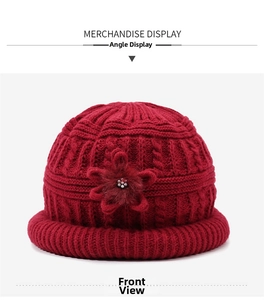 Detail of red cable-knit winter hat for women featuring a 3D flower with pearl accent