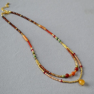 Detail of multi-layer beaded necklace featuring vintage stone beads and golden hardware