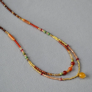 Detailed macro of layered necklace featuring colorful beads and gold finish accents