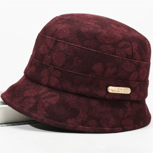 Detail shot of a dark burgundy cloche hat featuring embossed floral textures and gold plaque